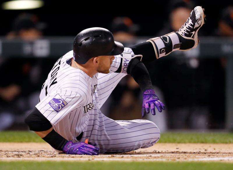 Colorado Rockies shortstop Trevor Story, front, reaches with his